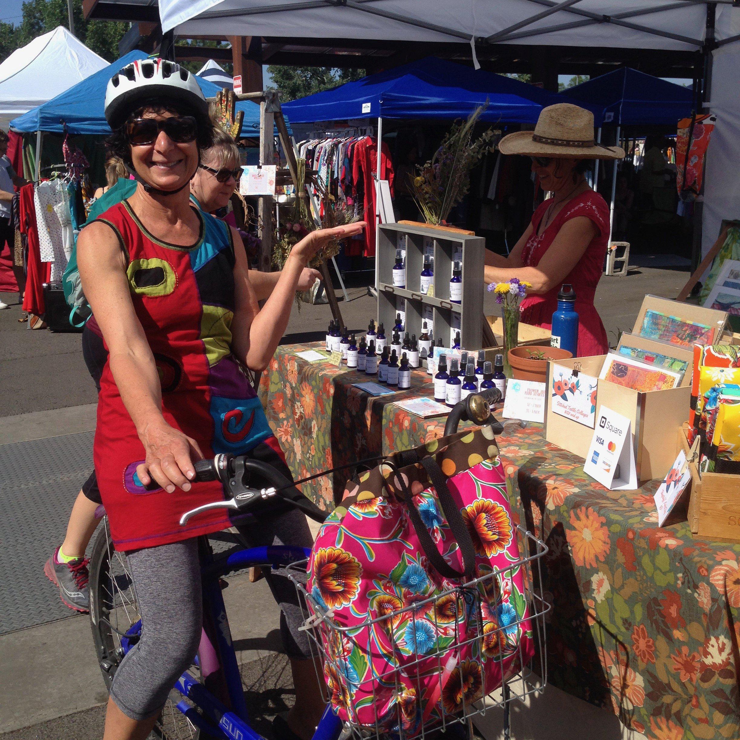 Woman on bicycle with her fuschia oilcloth Tallulah Art•Head market bag in bike basket